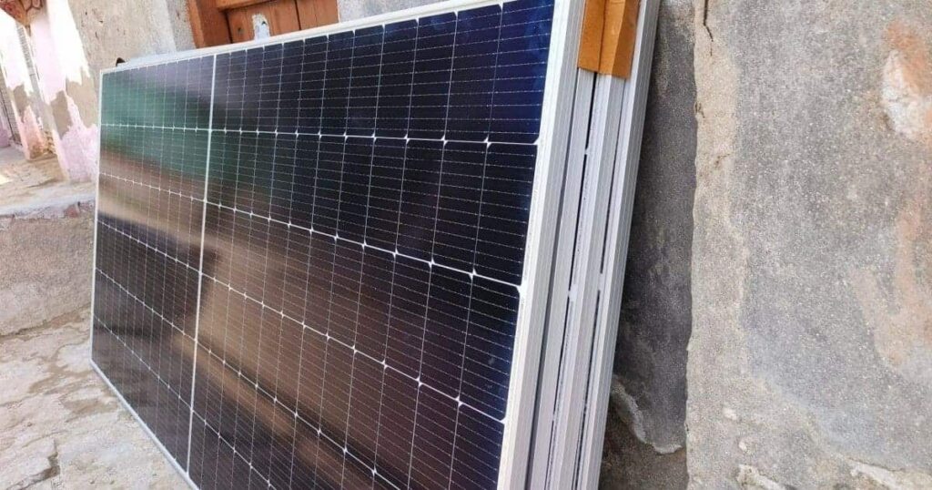 Des panneaux solaires monocristallins posés contre un mur avant leur installation. 