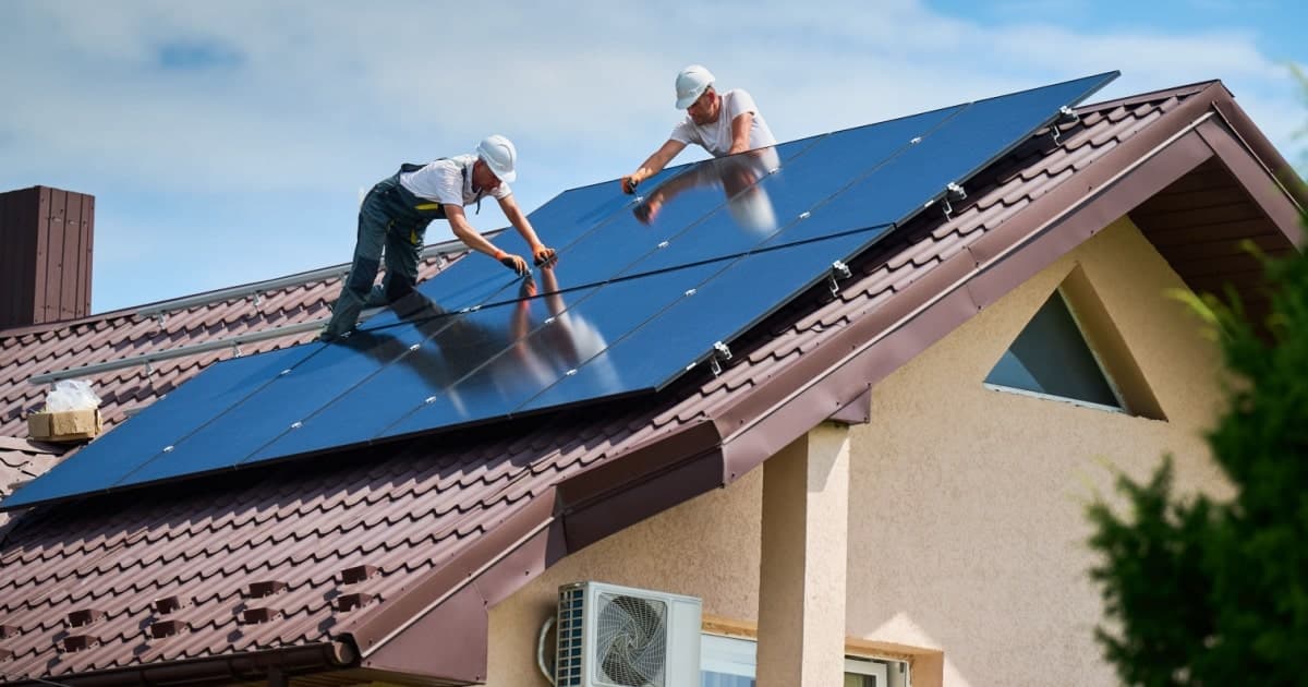 Deux installateurs fixent des panneaux solaires sur une toiture belge 