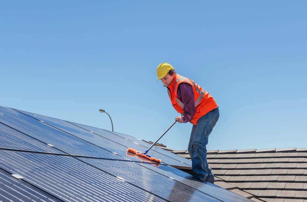 ouvrier nettoyant les panneaux solaires sur le toit
